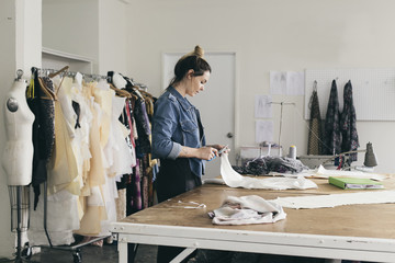 Young female seamstress cutting pattern in fashion studio
