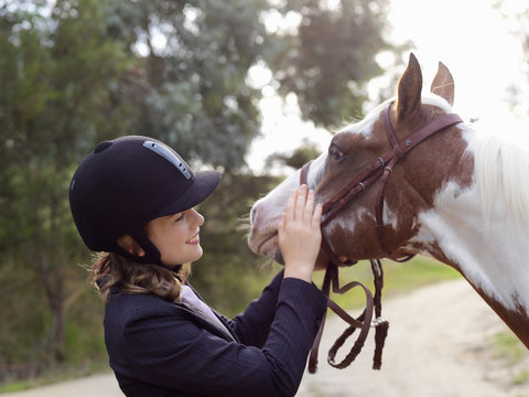 Teenage girl petting horse