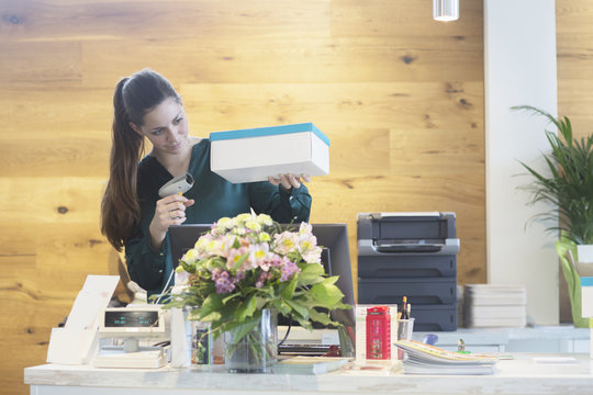 Female sales assistant using barcode reader on shoe box in shoe shop