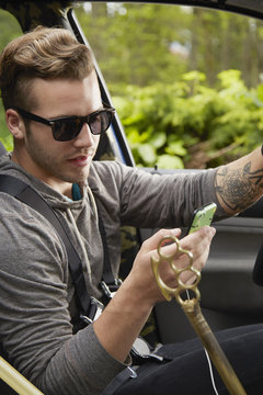 Portrait of man driving wearing sunglasses and using smart phone