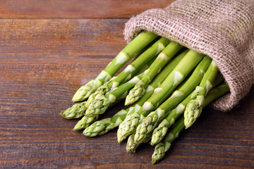 useful asparagus in the pouch of burlap on brown wooden background