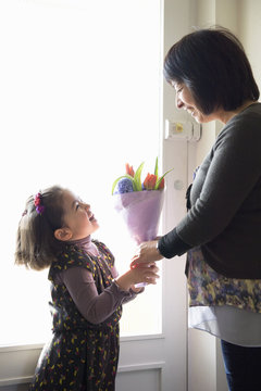 Young girl giving mother flowers