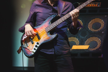 Obraz na płótnie Canvas Bass guitar player on a stage near speakers