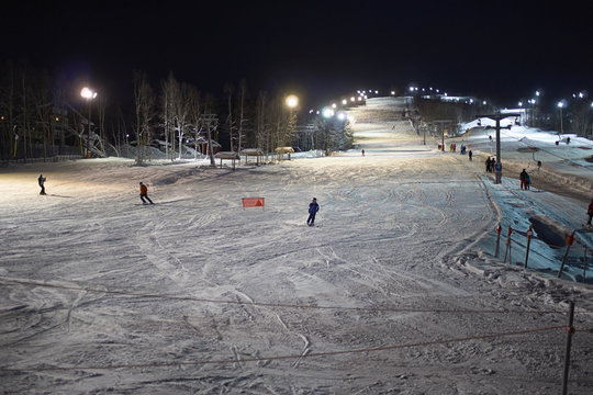 Skiers skiing down ski slope at night, Hemavan, Sweden