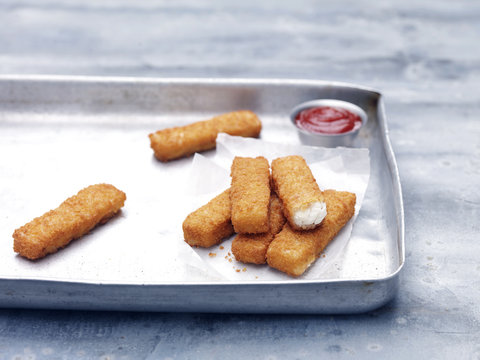 Baking tin with fried chunky cod breaded fish fingers with tomato ketchup