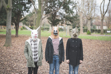 Three sisters wearing animal masks posing in park