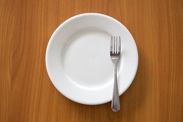 white circle ceramic dish with silver fork on wood table