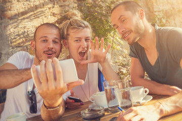 Three friends using cellphone and having a conversation in a coffee shop.