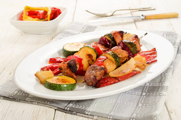grilled hungarian meat vegetables skewers on an oval plate