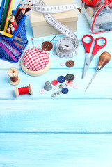 tools tailor spools threads buttons needle sewing blue wooden background
