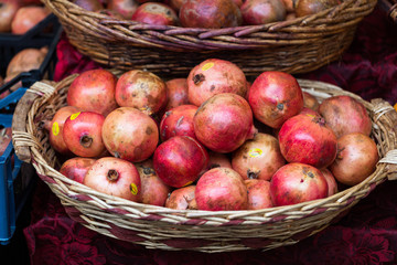 Group of fresh ripe pomegranate fruits in basket on display at local market