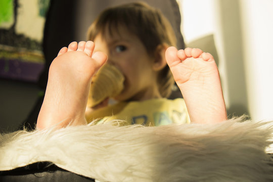 Young boy drinking from beaker, focus on feet