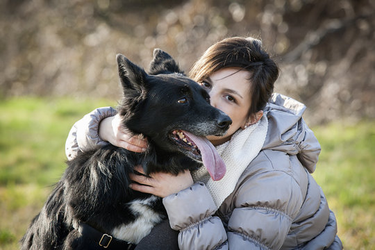 Portrait of mid adult woman kissing her dog in field