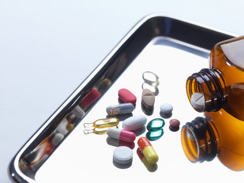 Close up of variety of medical drugs pouring from pill bottle on surgical tray