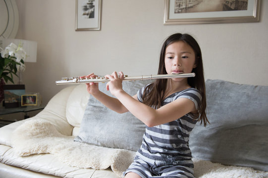 Girl playing the flute on sofa