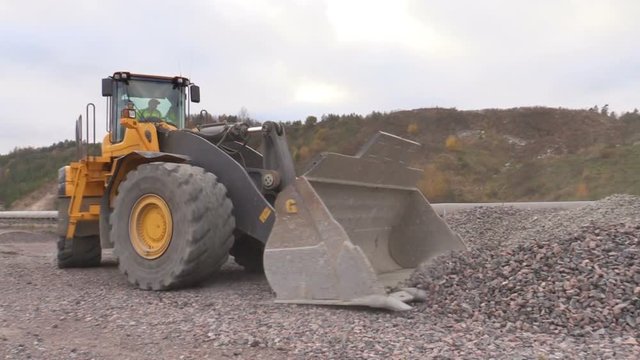 Wheel loader construction equipment shovels gravel.