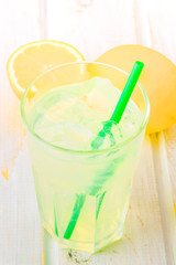 glass of lemonade with straw on wood
