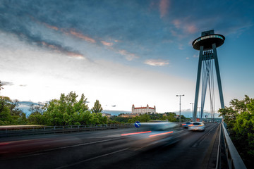 View on the Modern bridge with observation deck and restaurant called UFO and castle in Bratislava city at the sunset. Long exposure technique with motion of cars © rh2010
