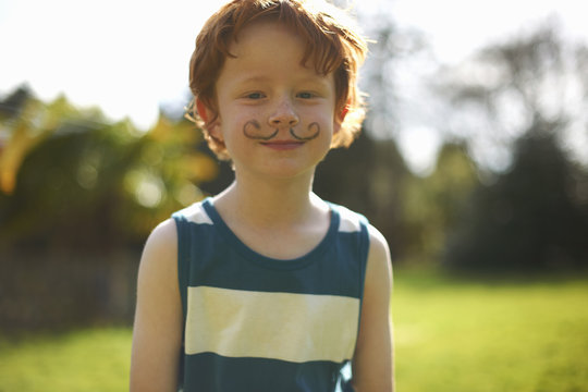 Portrait of young boy with drawn on moustache