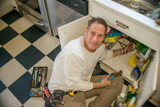 Handyman fixing kitchen sink pipe