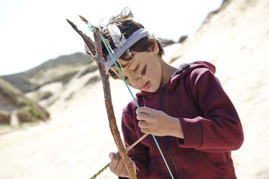 Young boy wearing fancy dress, holding home-made bow and arrow