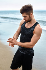 Portrait Of Healthy Handsome Athletic Man With Fit Muscular Body In Summer Sportswear Standing On Ocean Or Sea Beach. Sporty Male Resting After Exercising And Running Outdoor. Sports, Fitness Concept
