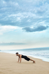 Sports. Sporty Handsome Male Doing Push Ups Exercise During Outdoor Workout At Beach. Fit Athletic Man With Muscular Body Exercising On Sand, Training Near Ocean. Fitness, Healthy Lifestyle Concept