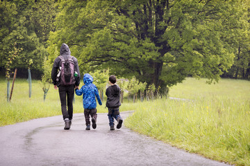 Father with children on rain spring walk