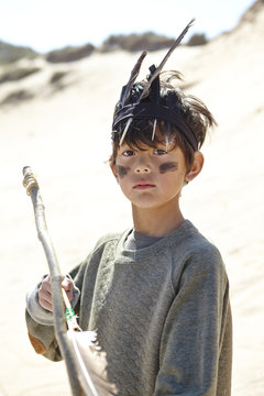 Young boy wearing fancy dress, holding home-made bow and arrow