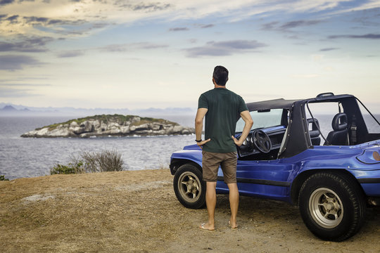 Rear view of male tourist looking out to Branca island, Buzios, Rio de Janeiro, Brazil