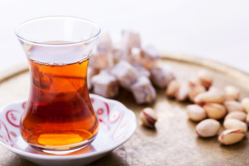 Turkish tea in traditional glass cup, with traditional sweets on