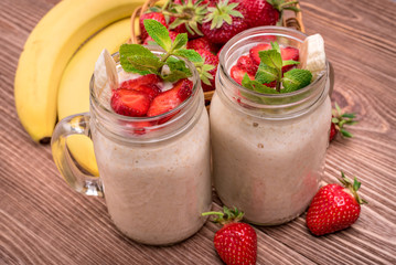 Smoothies with oatmeal ,strawberry, banana in glass jars on a wooden background.