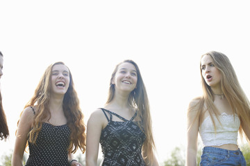 Four teenage girls laughing and chatting in park