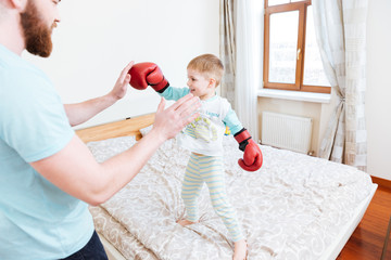 Little boy in boxing gloves playing with his dad