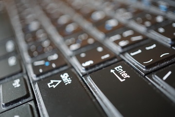 Detail of a black dusty laptop keyboard with a focus on an Enter key 