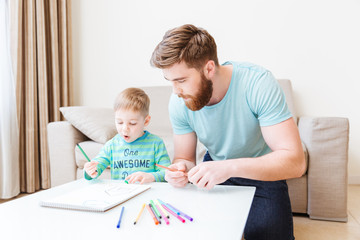 Father and son drawing in living room at home