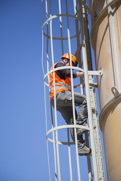Worker climbing smoke stack ladder