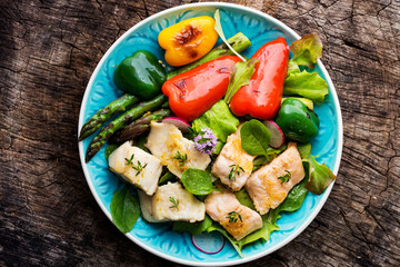 Fish fillets with vegetables on wooden background