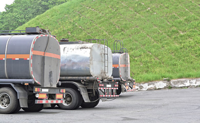 Three tanker trucks stand in a line, rear view.