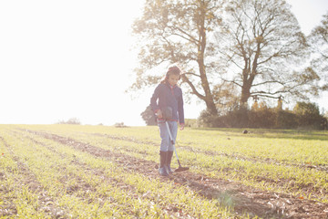 Girl wearing headphones using metal detector in sunlit field
