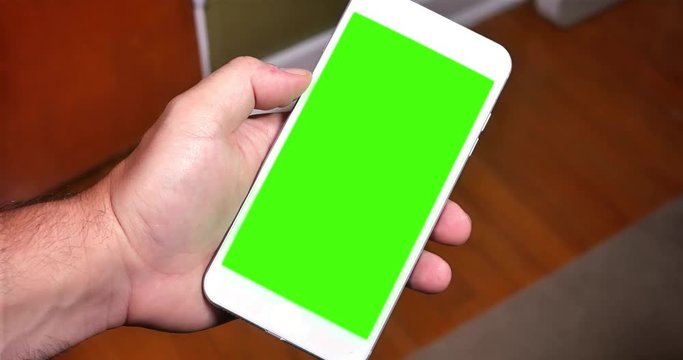 A man holds a smartphone in portrait mode. Green screen with optional luma matte included.	