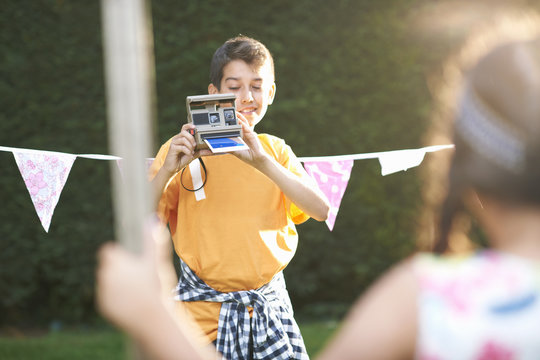 Boy photographing girl using instant camera