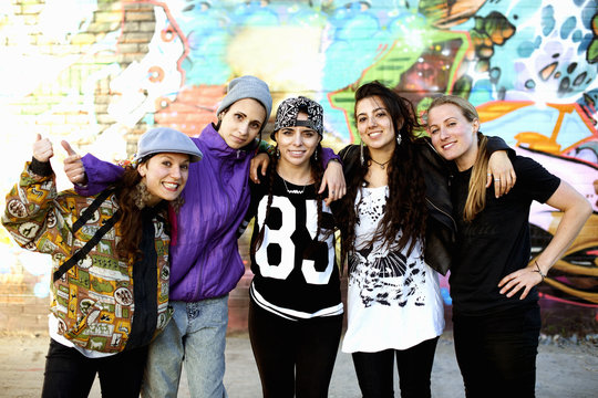 Young women standing with arms around each other, looking at camera