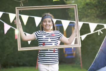 Girl looking through picture frame, looking at camera smiling