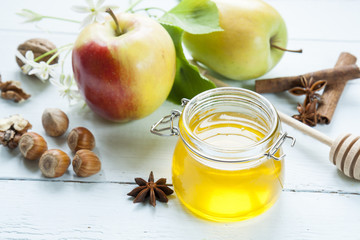 Apple and honey, traditional food of jewish New Year - Rosh Hashana, with spices, flowers and nuts on light wooden table