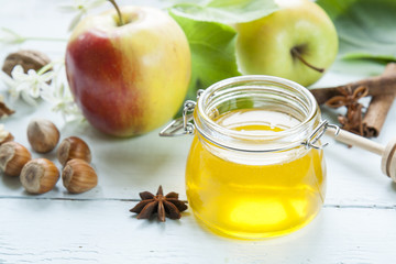 Apple and honey, traditional food of jewish New Year - Rosh Hashana, with spices, flowers and nuts on light wooden table