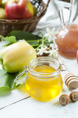 Apple and honey, traditional food of jewish New Year - Rosh Hashana, with spices, flowers and nuts on light wooden table