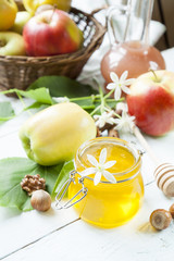 Apple and honey, traditional food of jewish New Year - Rosh Hashana, with spices, flowers and nuts on light wooden table