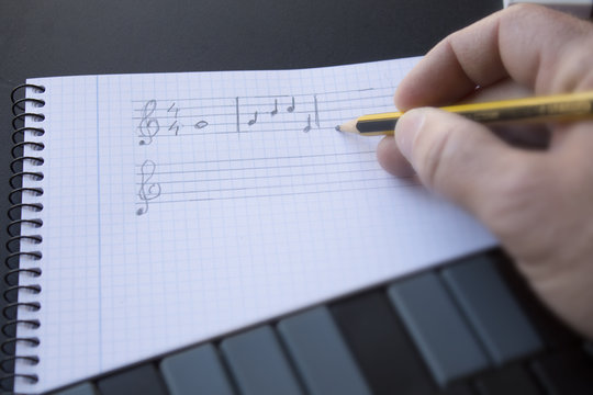 escribiendo notas musicales sobre pentagrama en un cuaderno