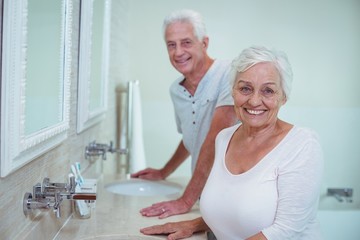 Senior couple standing by mirror in bathroom